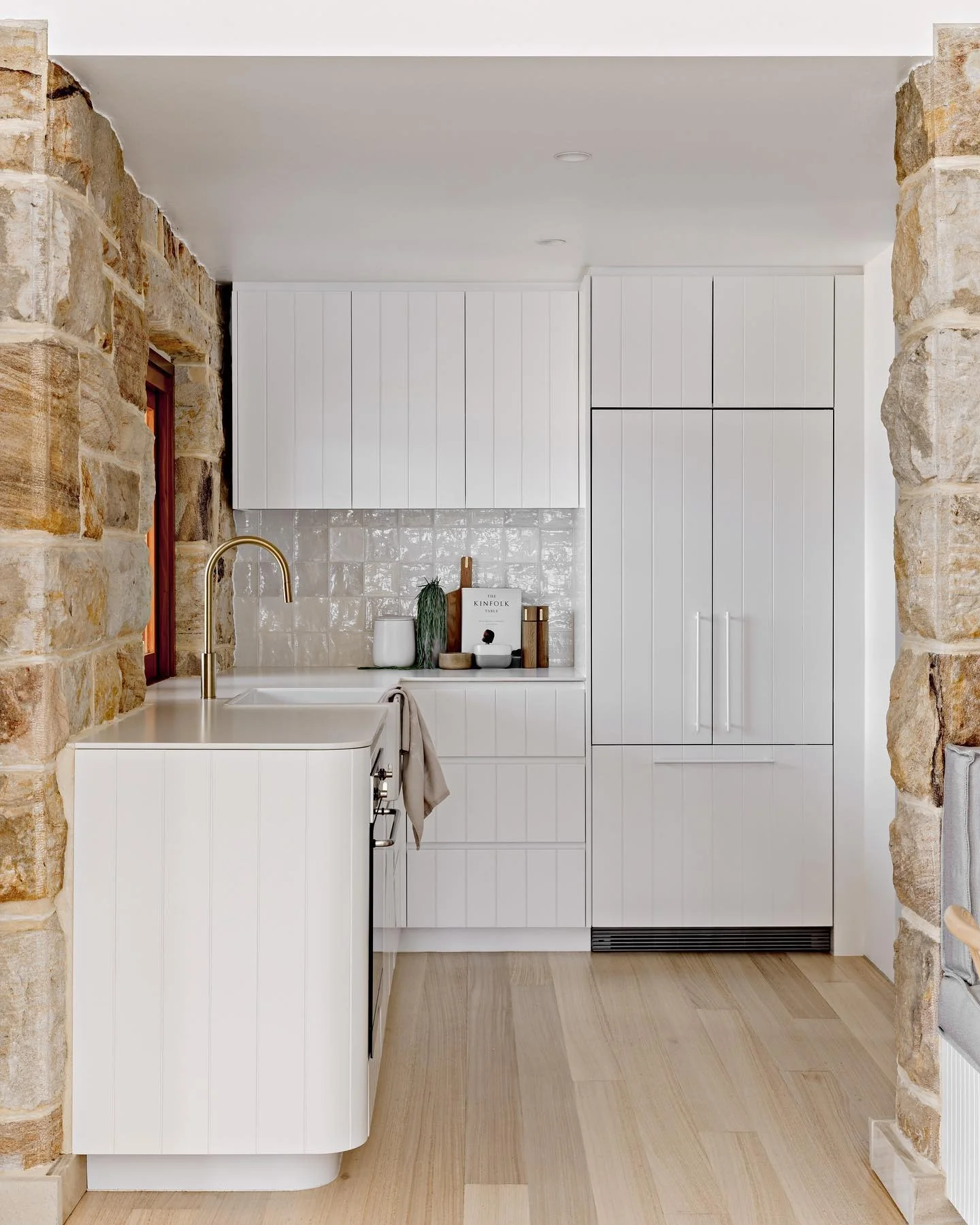 Curved White Cabinetry Softens a Stone Wall Kitchen