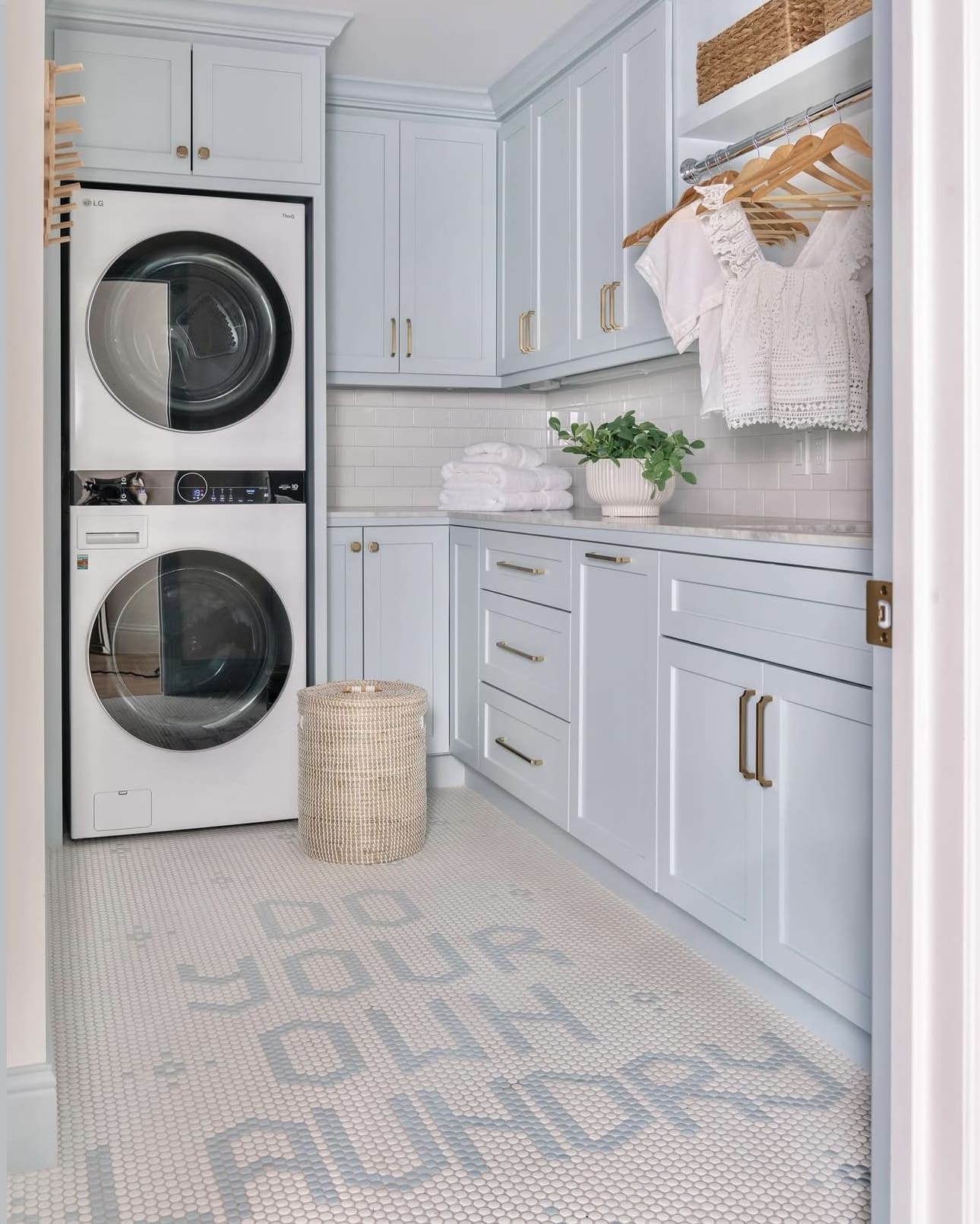 Pale blue cabinets with brass hardware create a serene laundry space