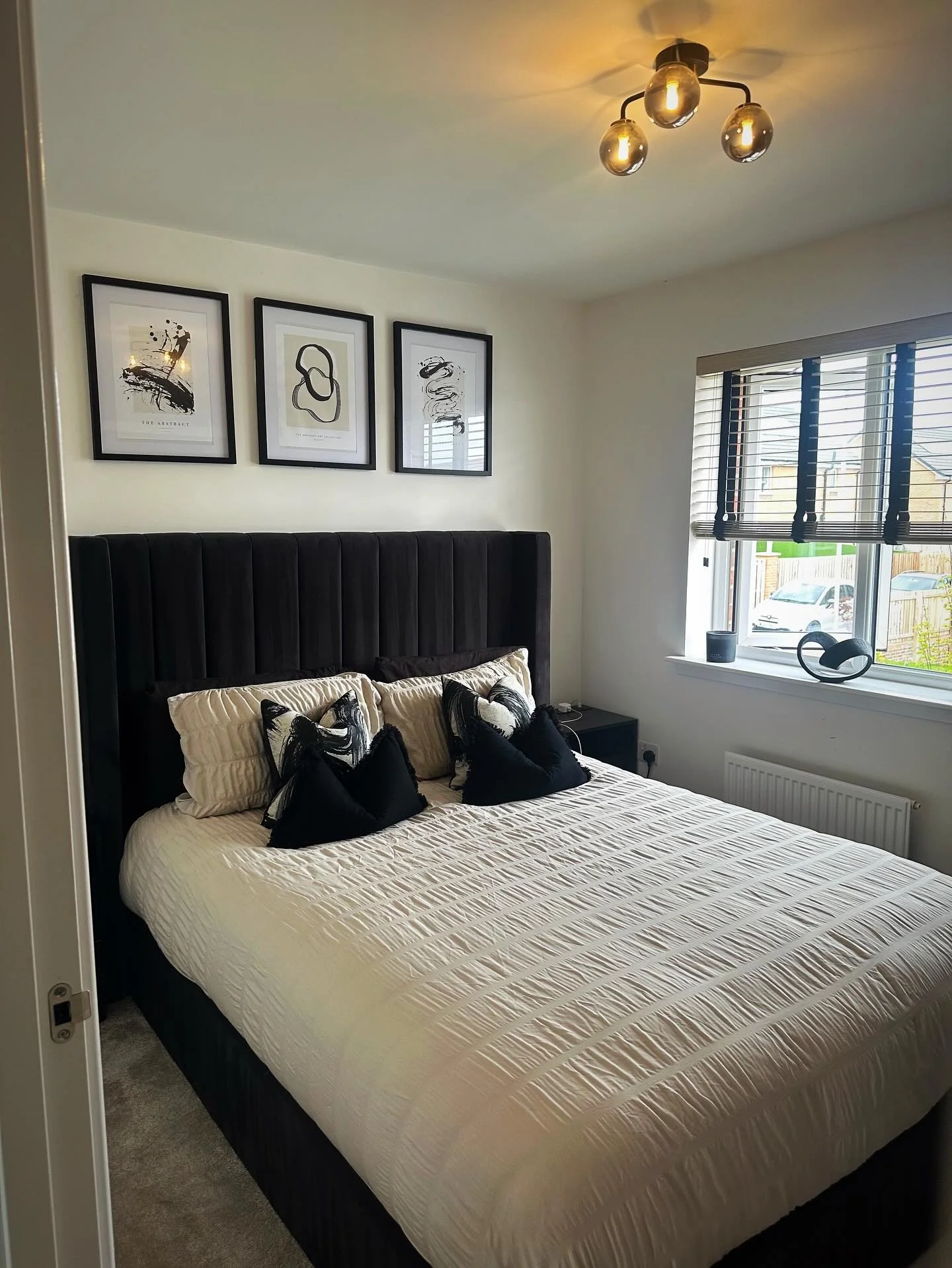 Three framed abstract prints add graphic interest above the bed