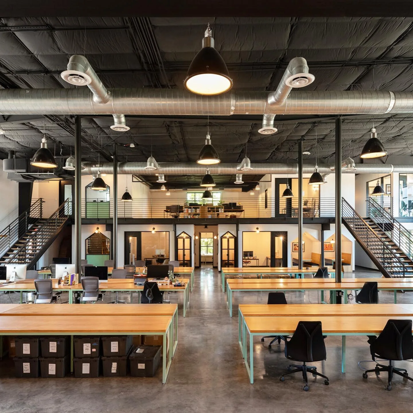 Black Pendant Lights Define Work Zones Above Wooden Desks