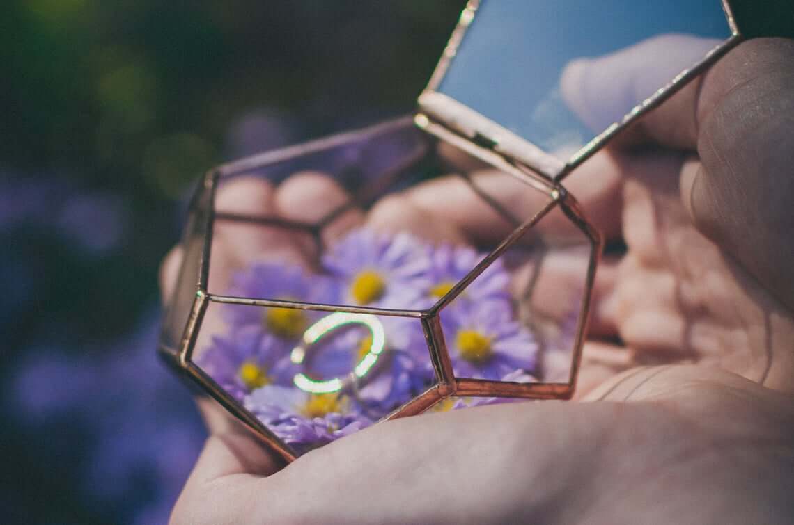 Geometric Glass Terrarium Holds Rings Amidst Purple Blooms