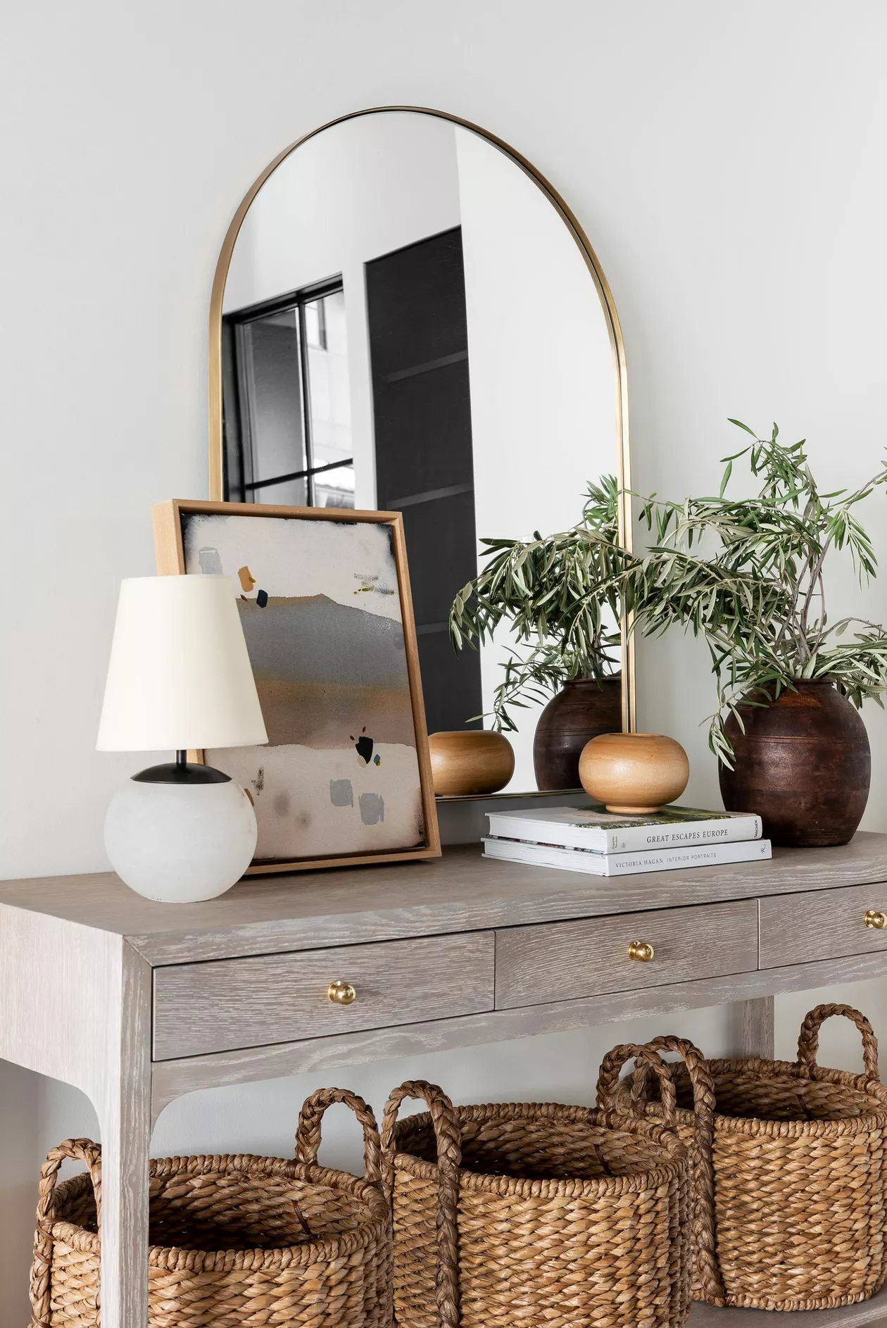 Layered Books Create a Base for Entryway Vases and Greenery