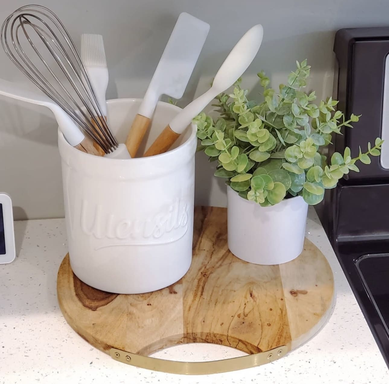 White Utensil Holder with Greenery on a Wood Slice Tray