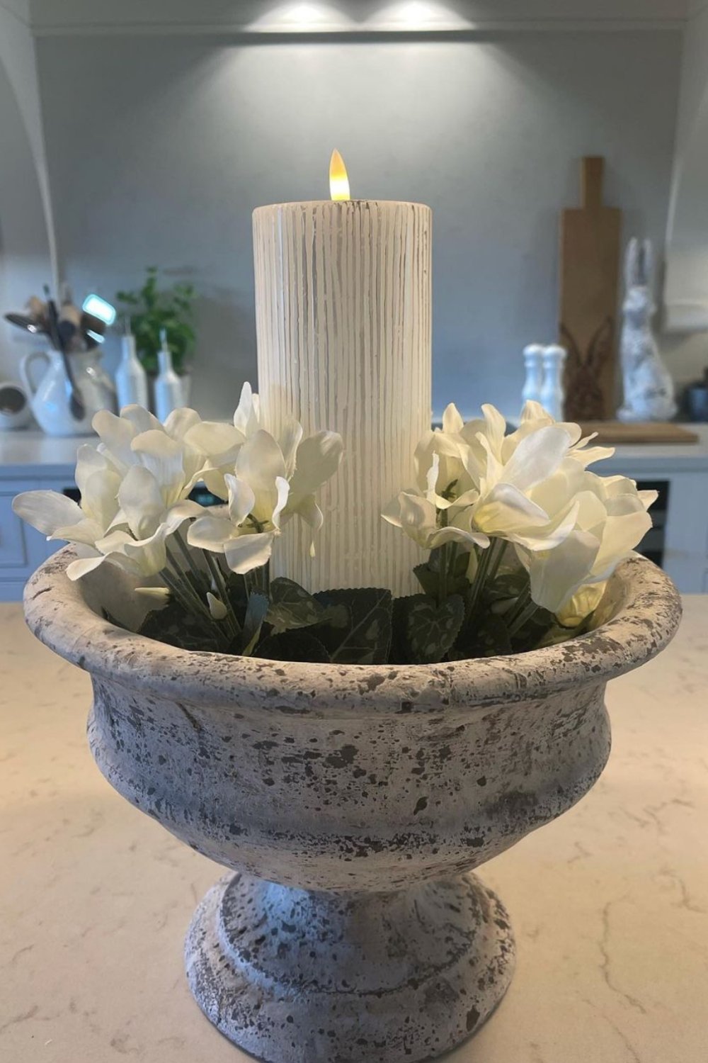 Distressed Urn Planter Holds Candle and White Flowers