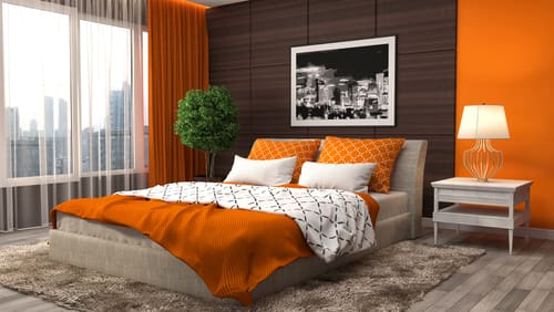 Orange and Dark Wood Walls Create a Dramatic Bedroom