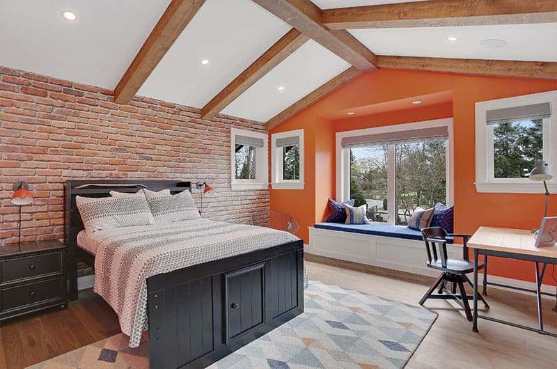 Orange Walls Frame Exposed Brick For A Cozy Bedroom