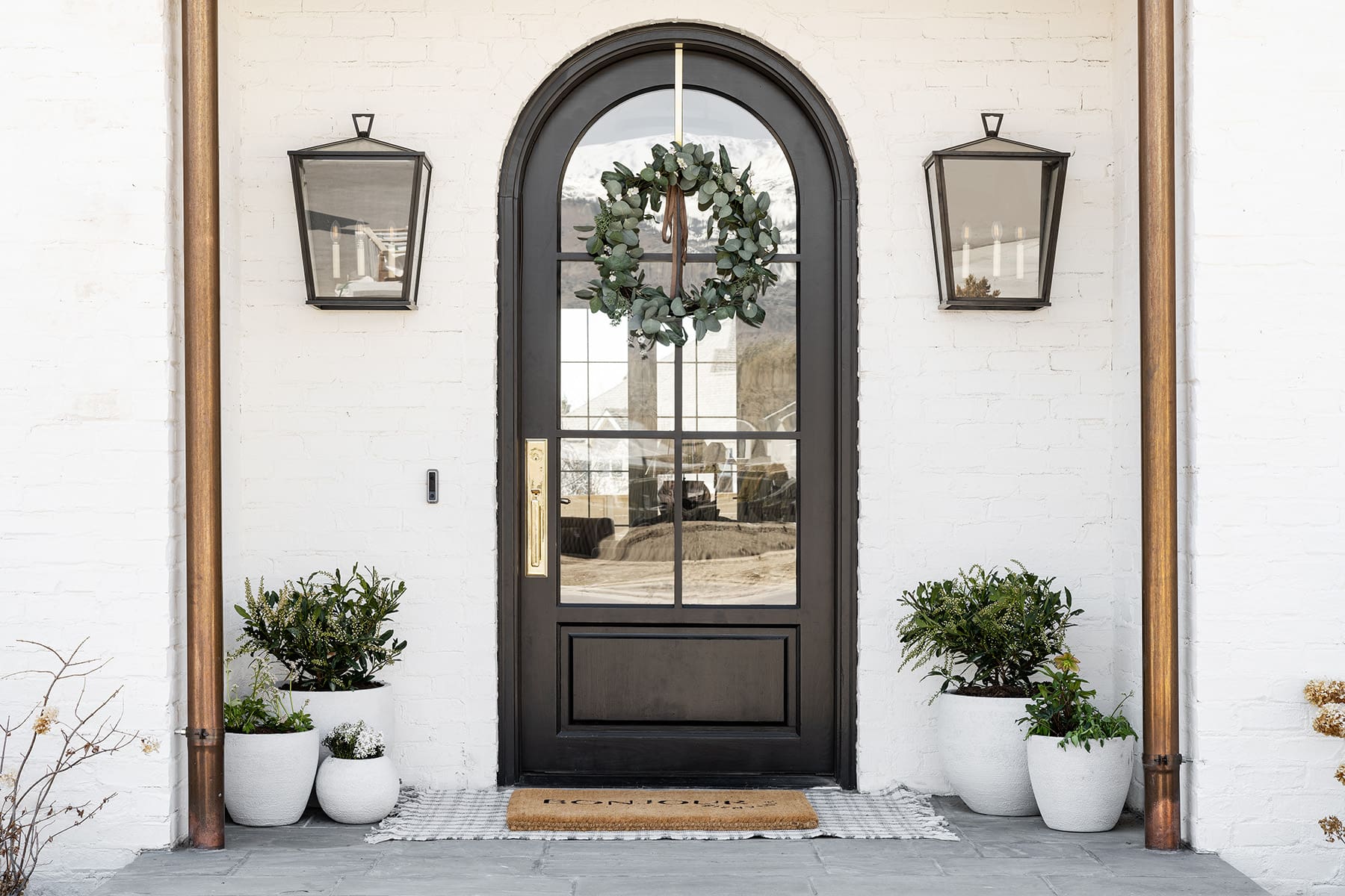 Arched Black Doorway with Eucalyptus Wreath and Brass Hardware