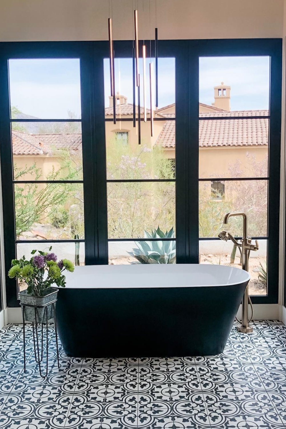 Ground the space with monochromatic floor tiles beneath a black tub