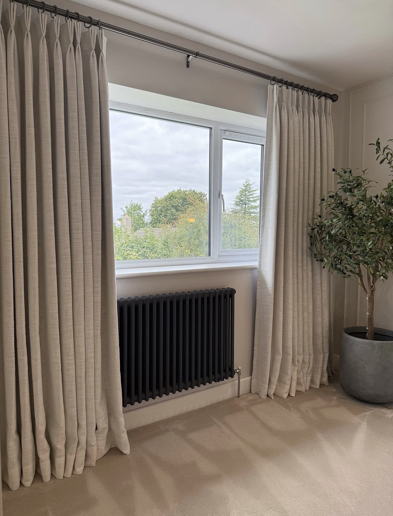 Pleated Neutral Curtains Soften Window and Radiator