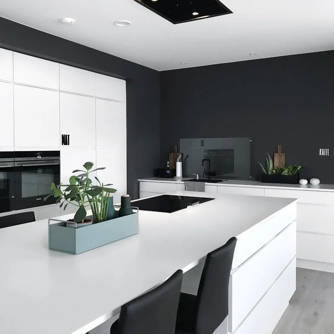 Matte black walls frame a sleek white kitchen island