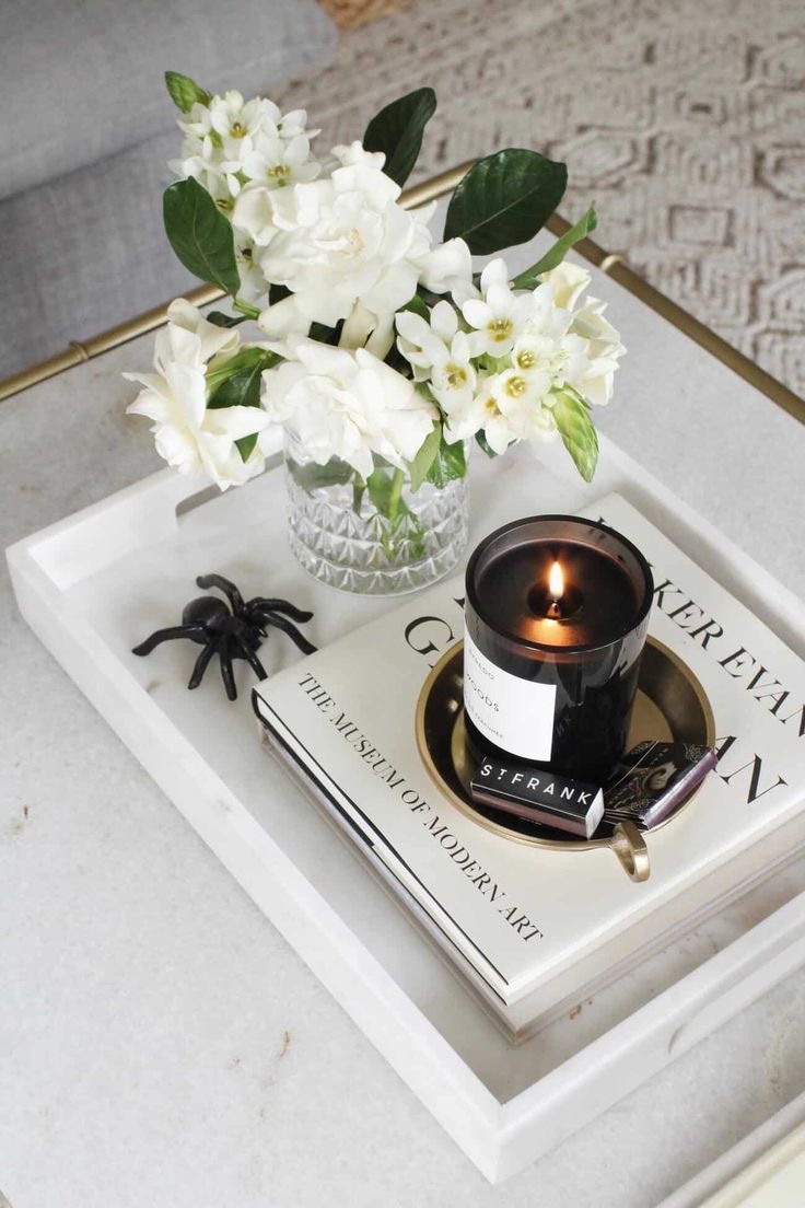 White Tray Holds A Layered Display Of Books And A Candle