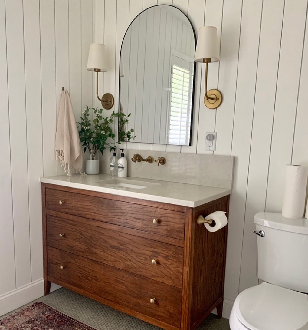 Arched Mirror Frames a Warm Wood Vanity