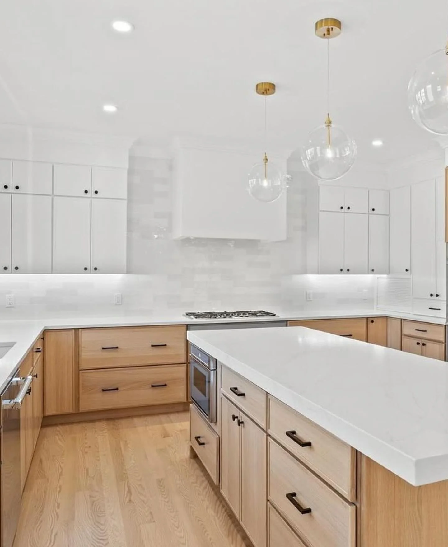 Clear Globe Pendants Add Warmth Above a White Countertop