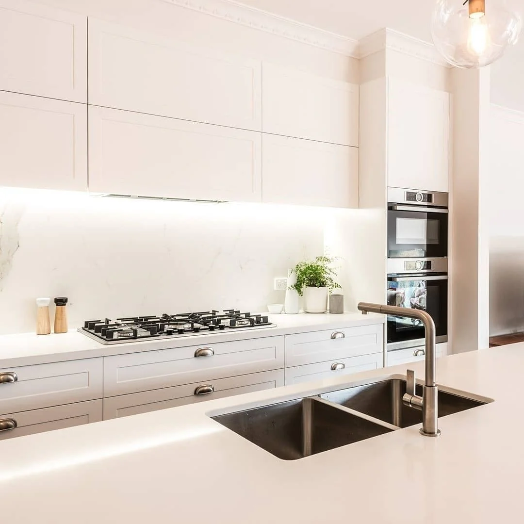 Under-cabinet lighting warms the marble backsplash
