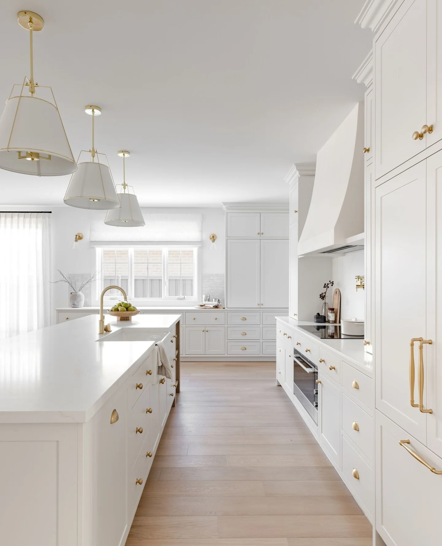 Brass Pendant Lights Add Warm Glow Above White Island